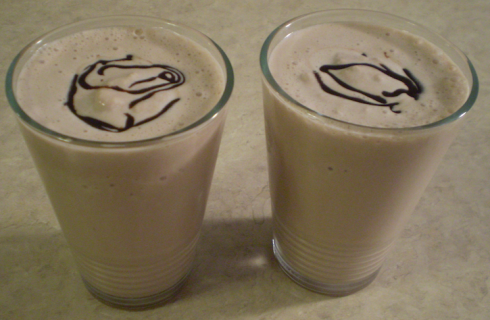 Two chocolate milkshakes garnished with chocolate syrup swirls.