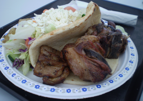 Roasted lamb with potatoes, pita bread and salad.